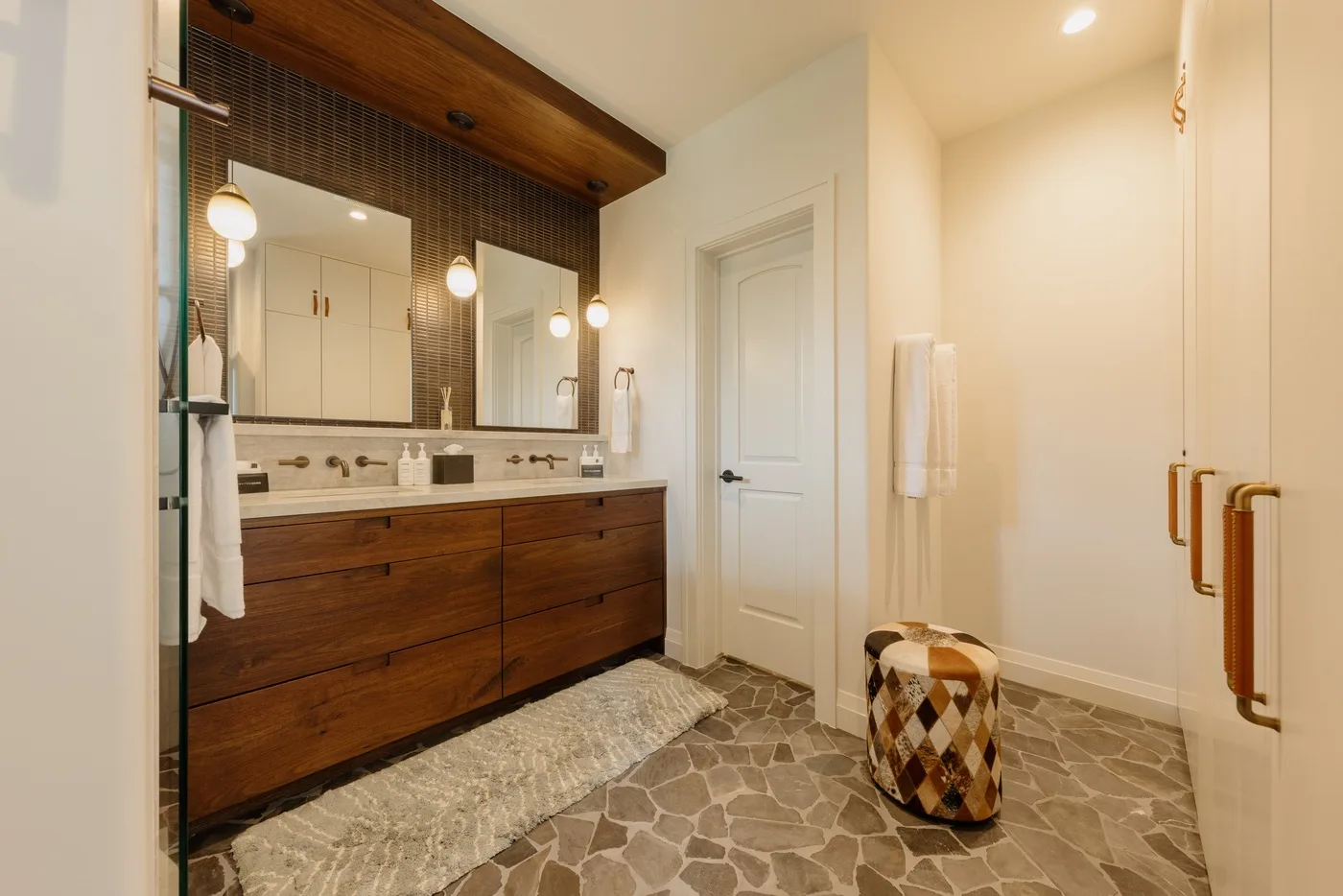 A bathroom vanity with a wide mirror and a stone-patterned floor.