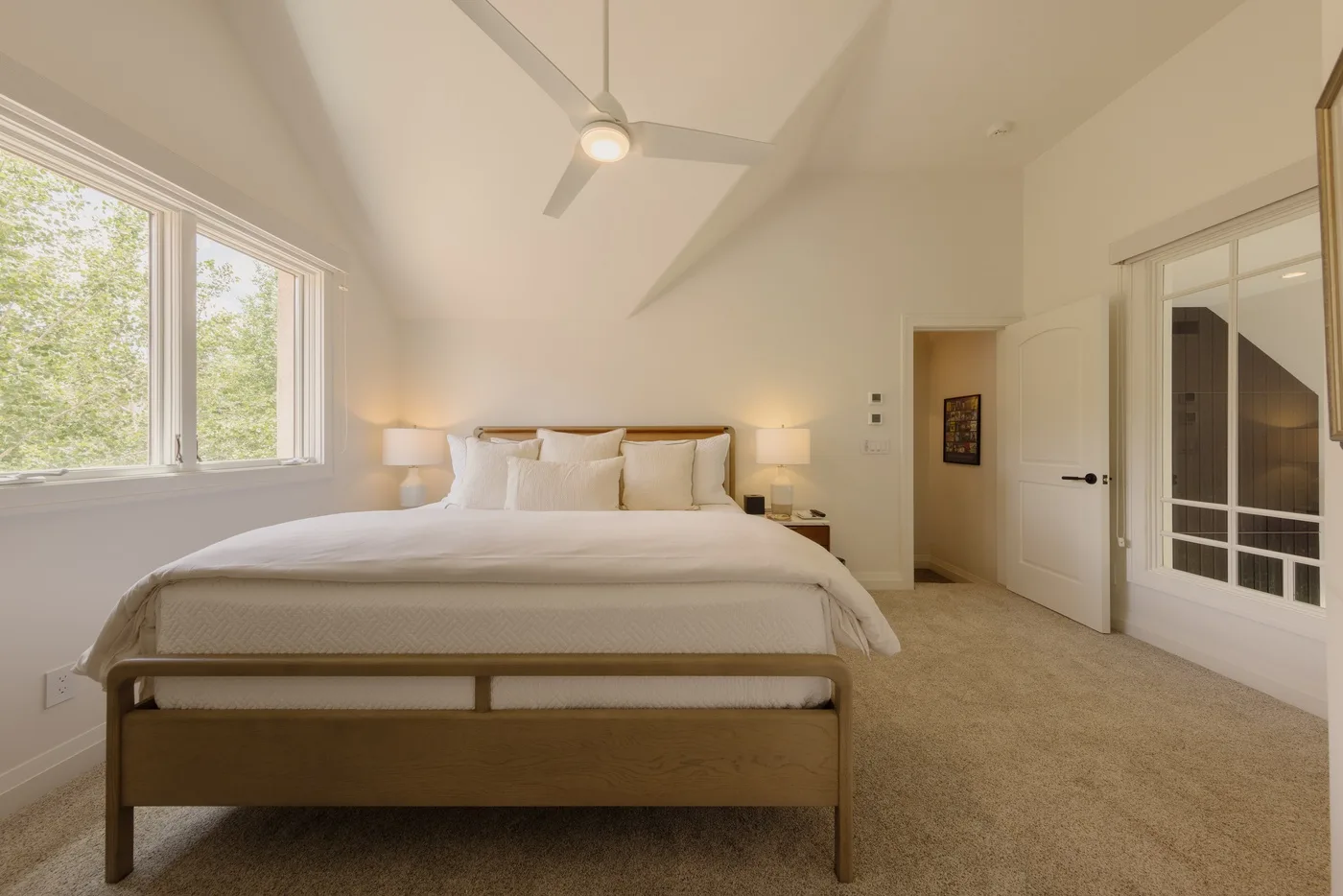 A bright bedroom with a large bed beneath a ceiling fan.
