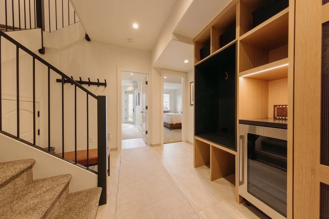 A bright hallway with a staircase and built-in wooden shelving.