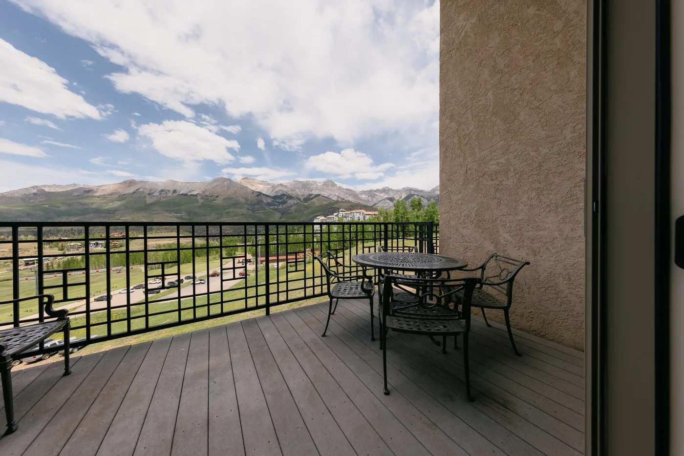 A furnished outdoor terrace overlooks a green valley and distant mountains.