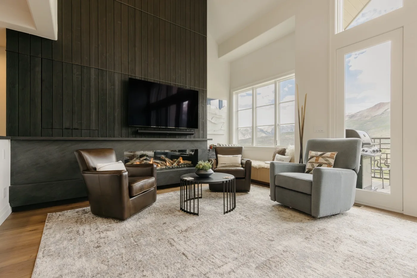 A bright living room with seating arranged around a coffee table beside a fireplace.