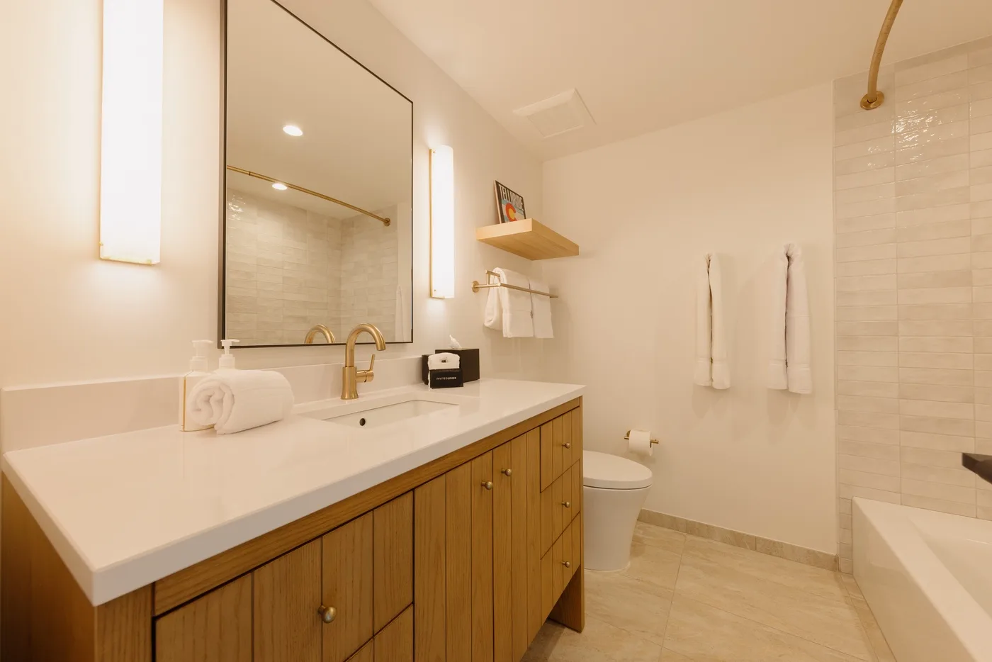A bright bathroom with a long vanity, sink, and shower.