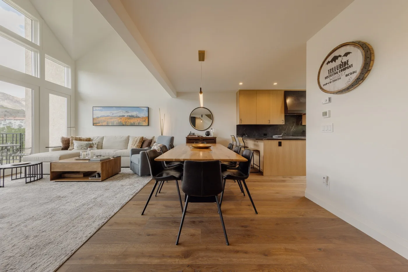 An open-plan living and dining area with a kitchen and large windows.