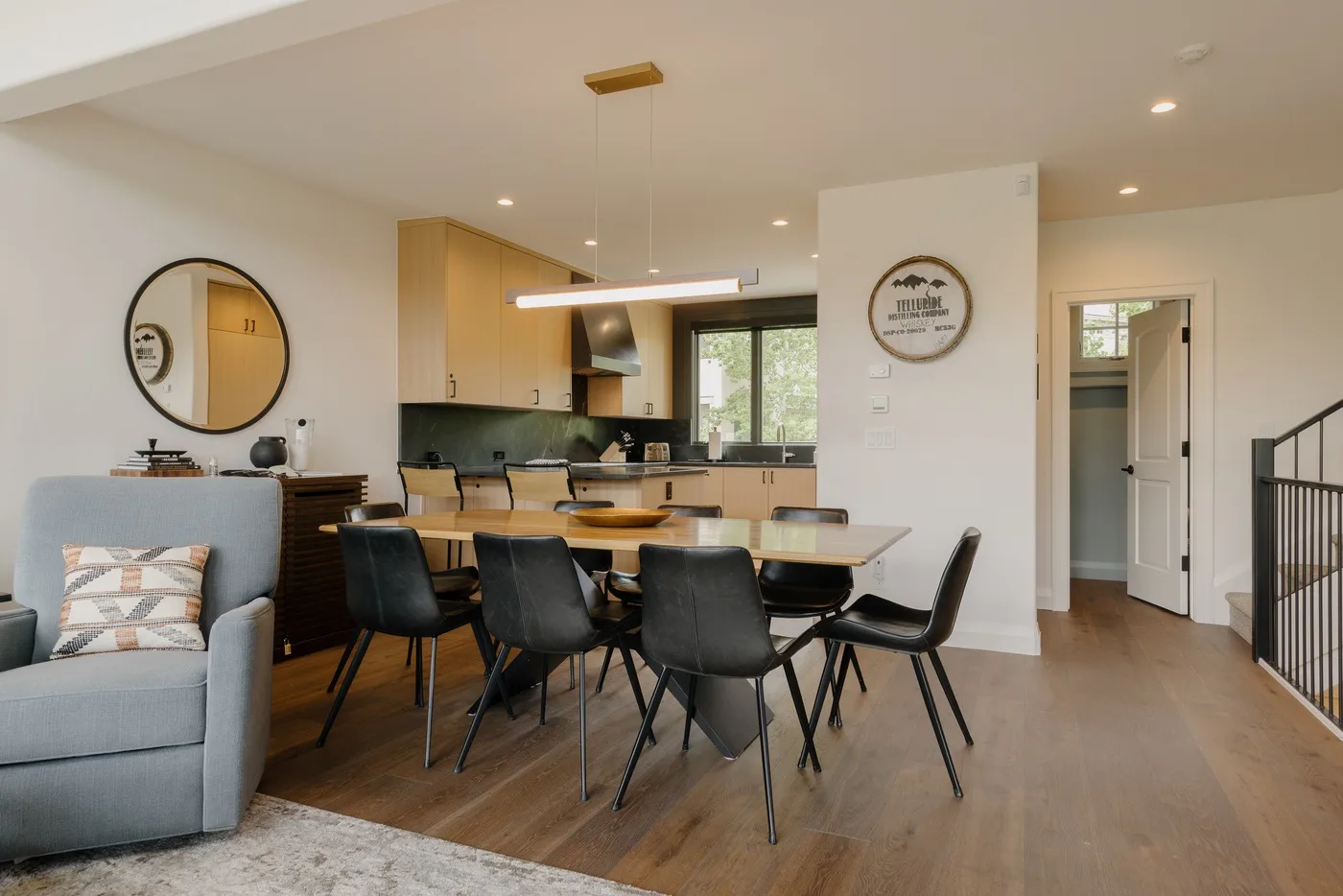 An open-plan dining and kitchen area with a table, seating, and light wood cabinetry.