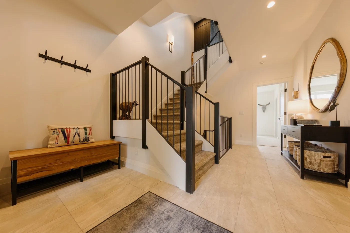 An interior entryway with a staircase, a wooden bench, and a console table.