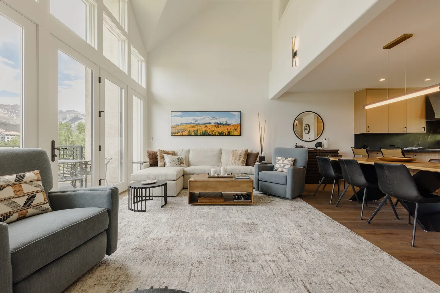 A bright living room with seating, a large rug, and tall windows.