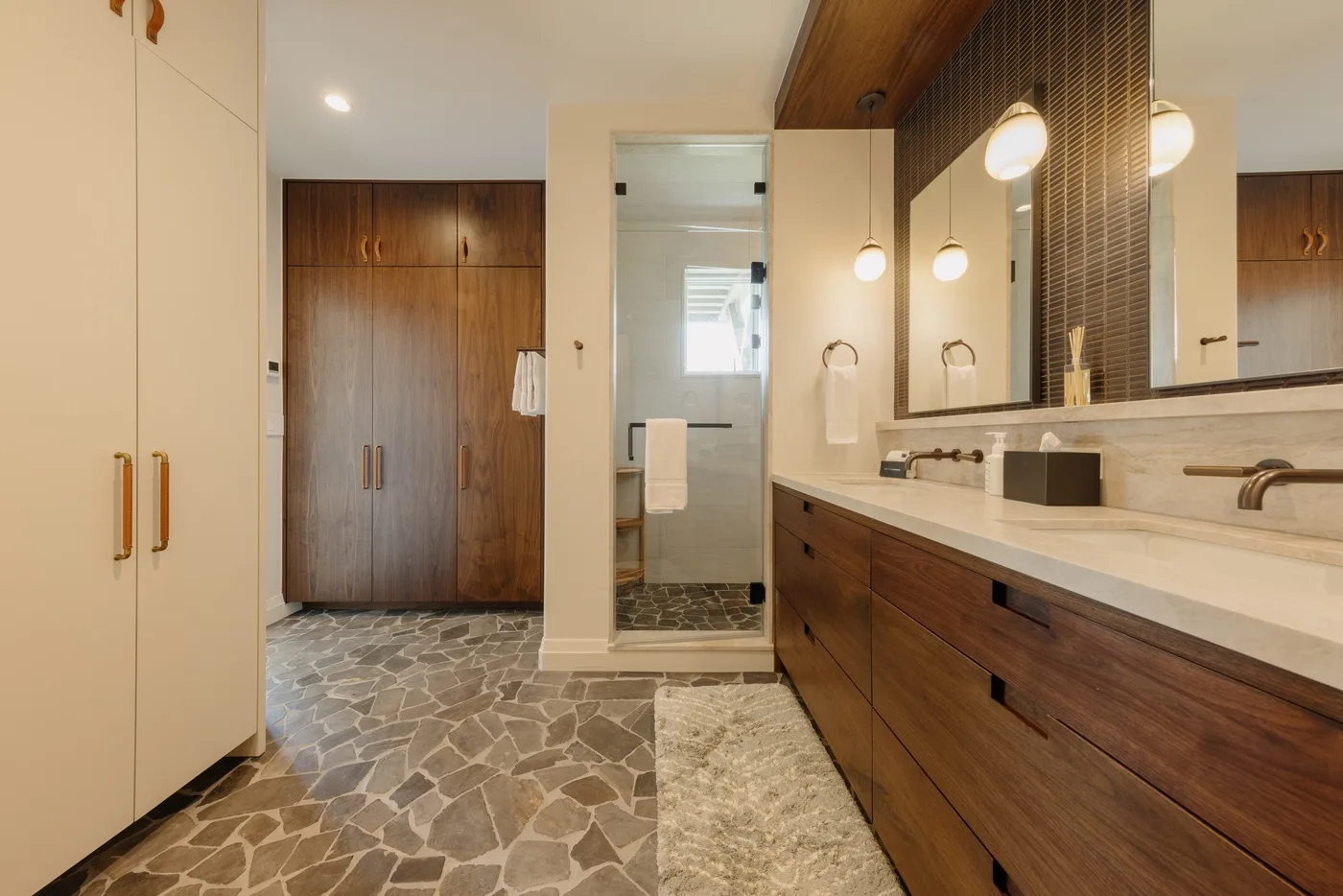 A bathroom vanity with a wide mirror and a walk-in shower area.