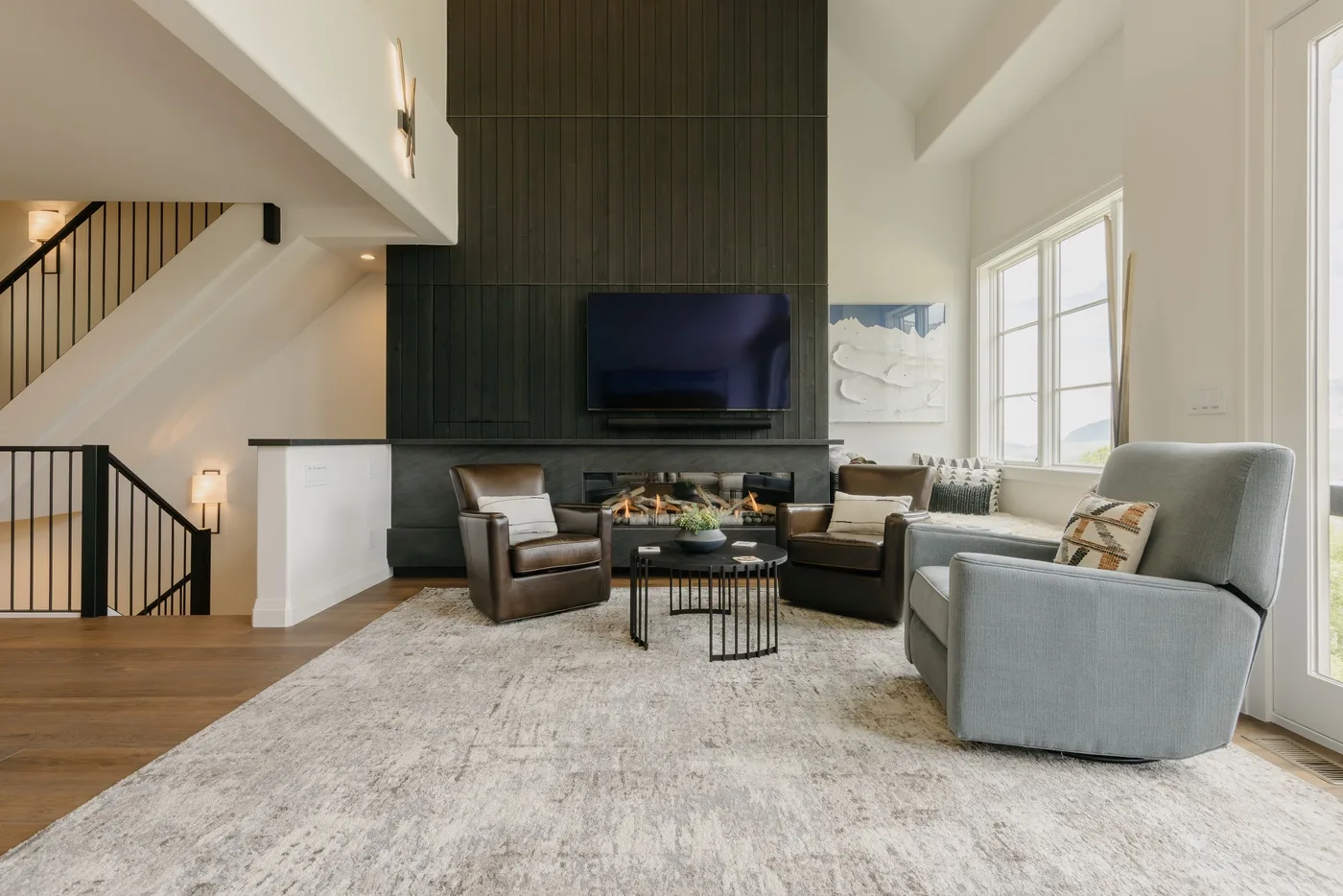 A spacious living room with seating arranged around a coffee table beneath a wall-mounted television.