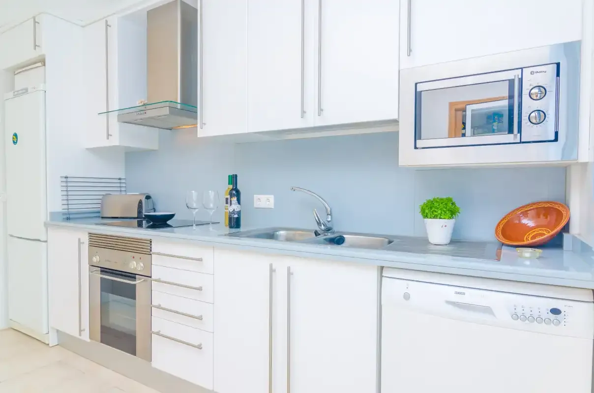 A bright kitchen with white cabinets, a countertop, and built-in appliances.