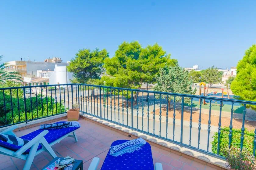 A sunny terrace overlooks a swimming pool, with lounge seating beside the railing.