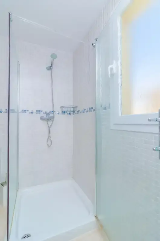 A bright shower area with white tiled walls and a window.