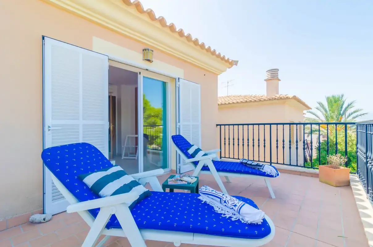 A tiled terrace with blue loungers overlooks nearby rooftops and greenery.