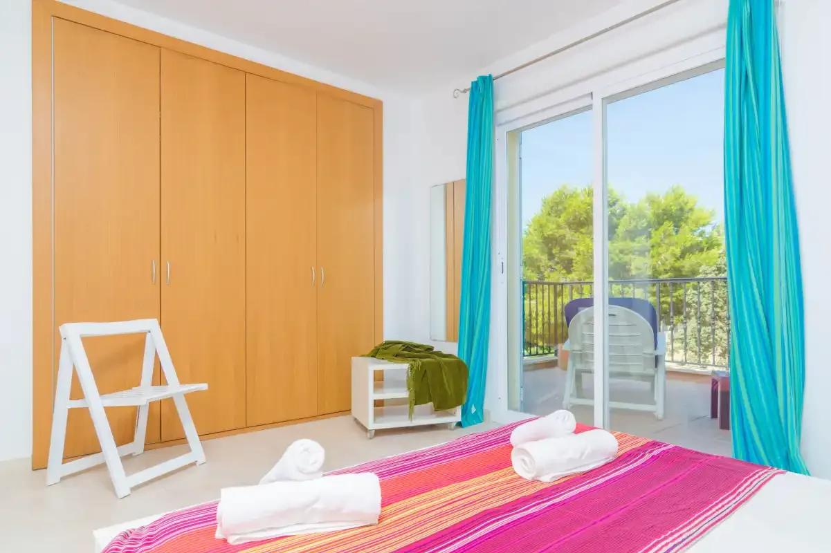 A bedroom with a colorful bedspread and sliding glass doors opening to a balcony.