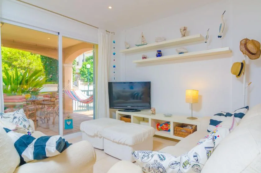 A bright living room with seating, a television, and sliding glass doors opening onto a patio.