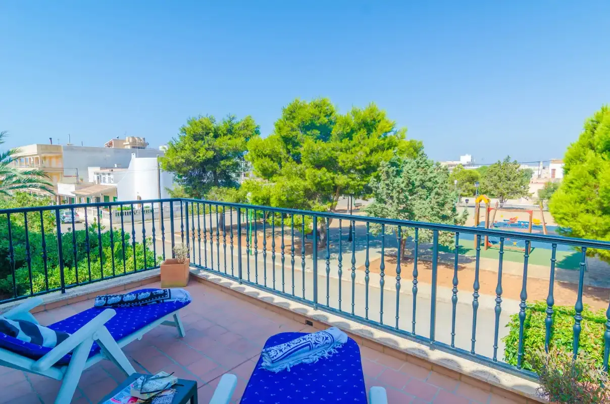 A tiled outdoor terrace overlooks trees, greenery, and nearby buildings.