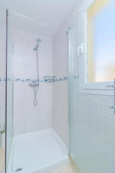 A tiled bathroom with a shower and a frosted window.