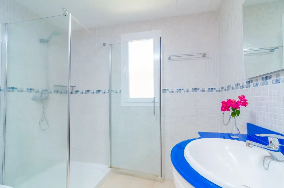 A bright bathroom with a glass shower and a blue-edged sink.