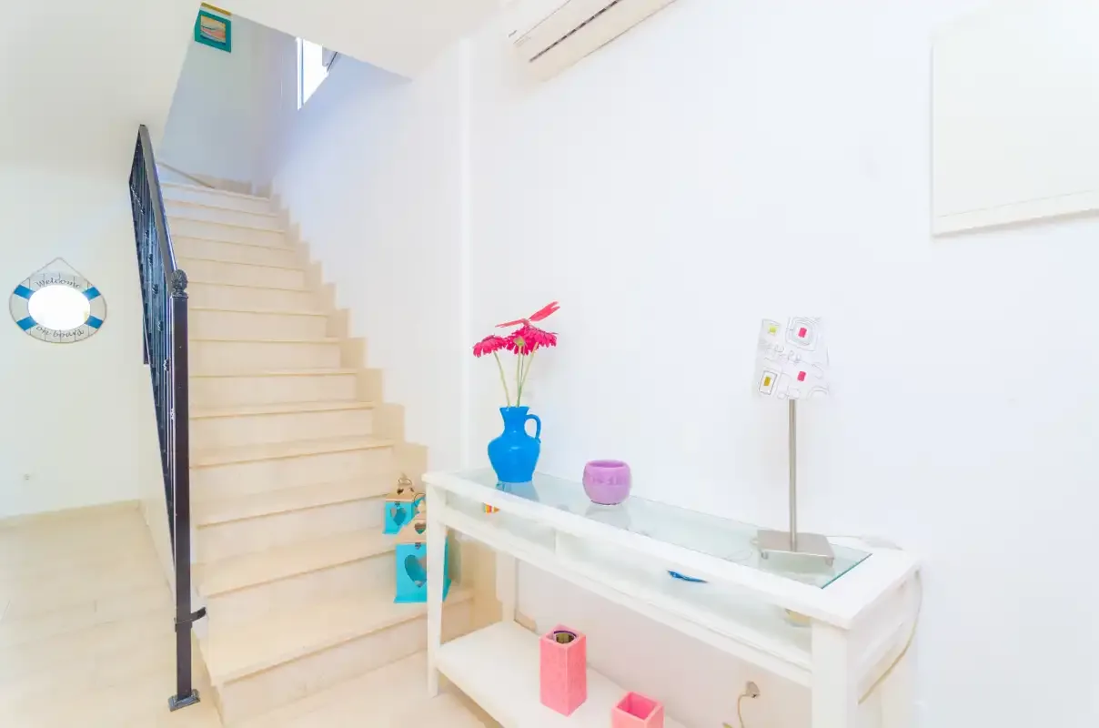 A bright interior entryway features a staircase and a white console table.