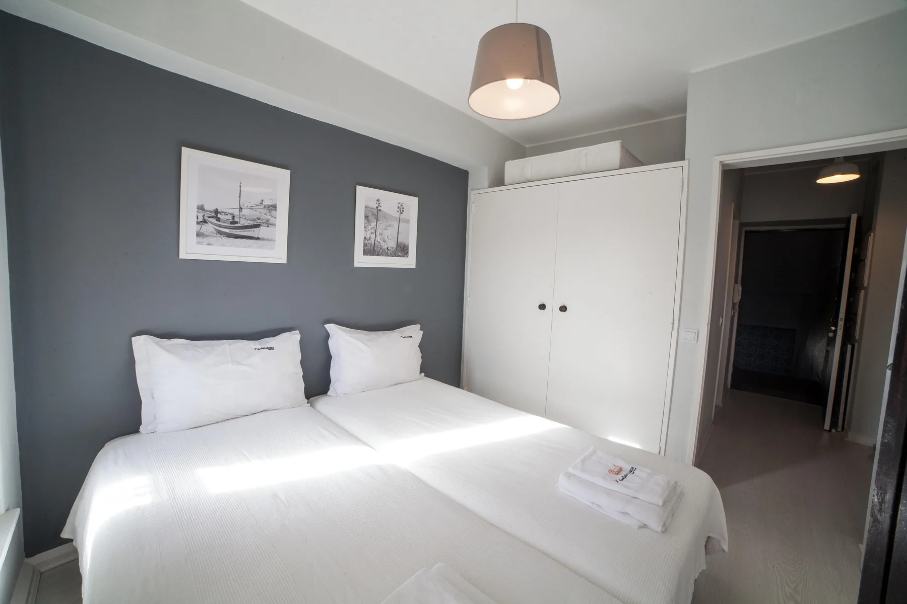 A bedroom with two beds, white bedding, and a built-in wardrobe.
