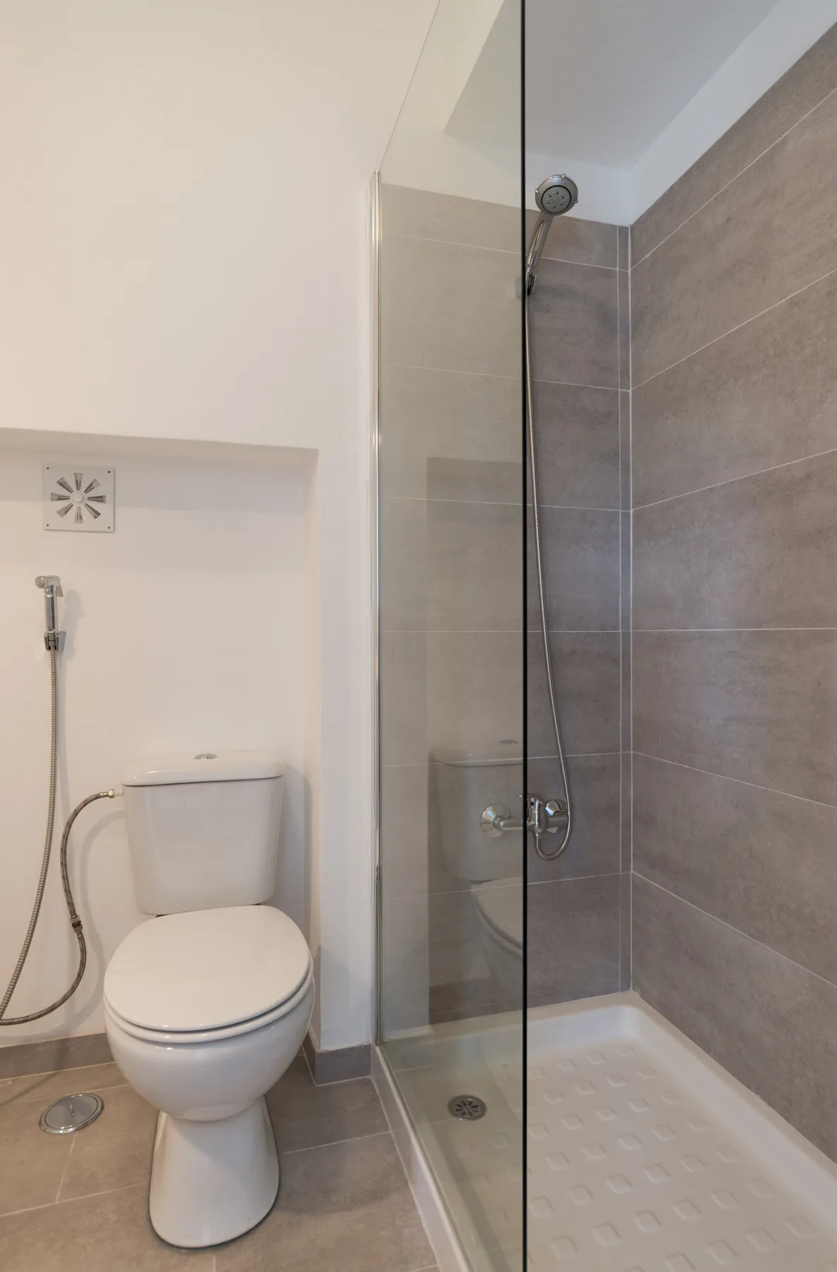 A bathroom with a toilet beside a glass-partitioned shower.