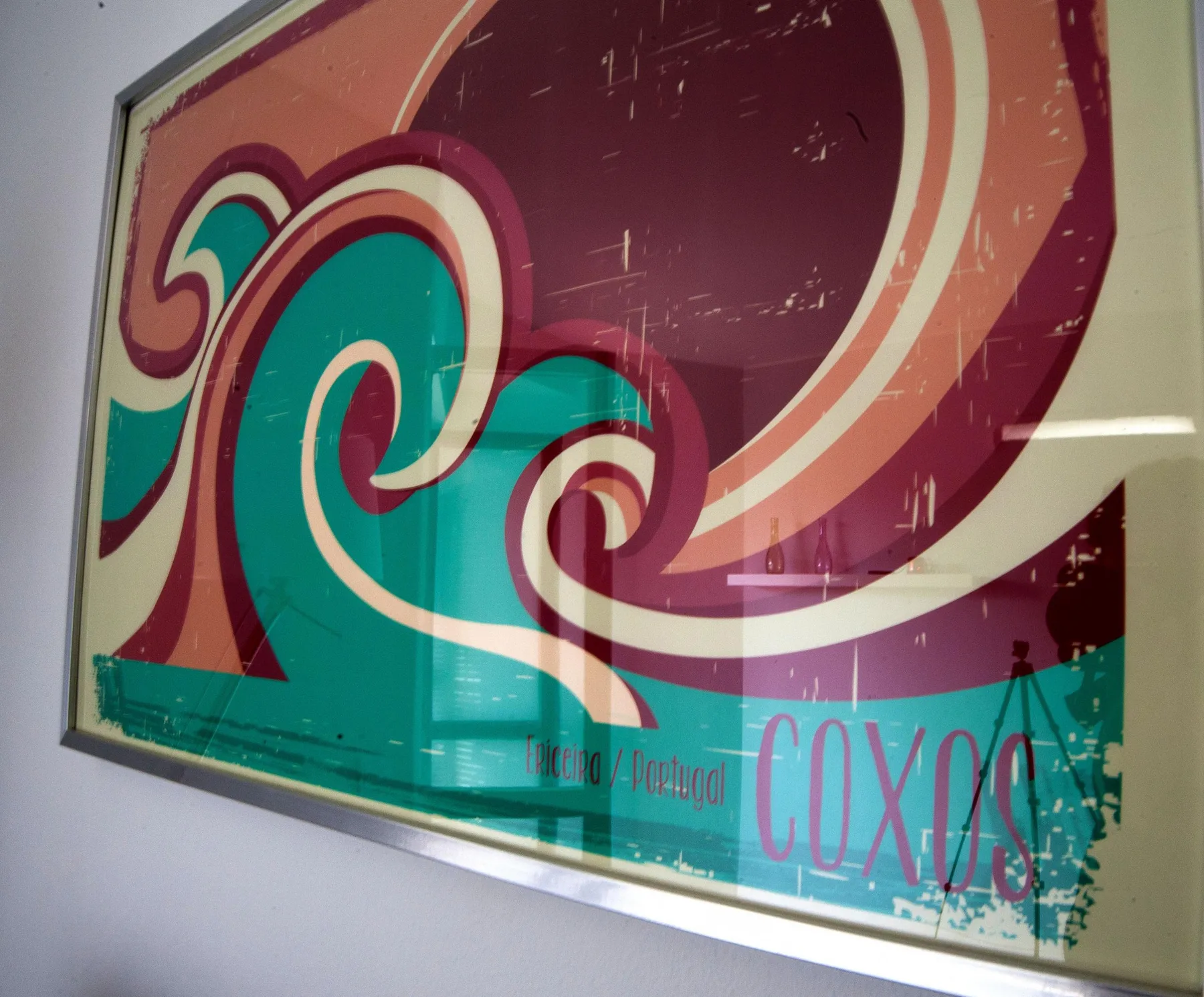 Framed colorful wave artwork hangs on a light-colored wall.