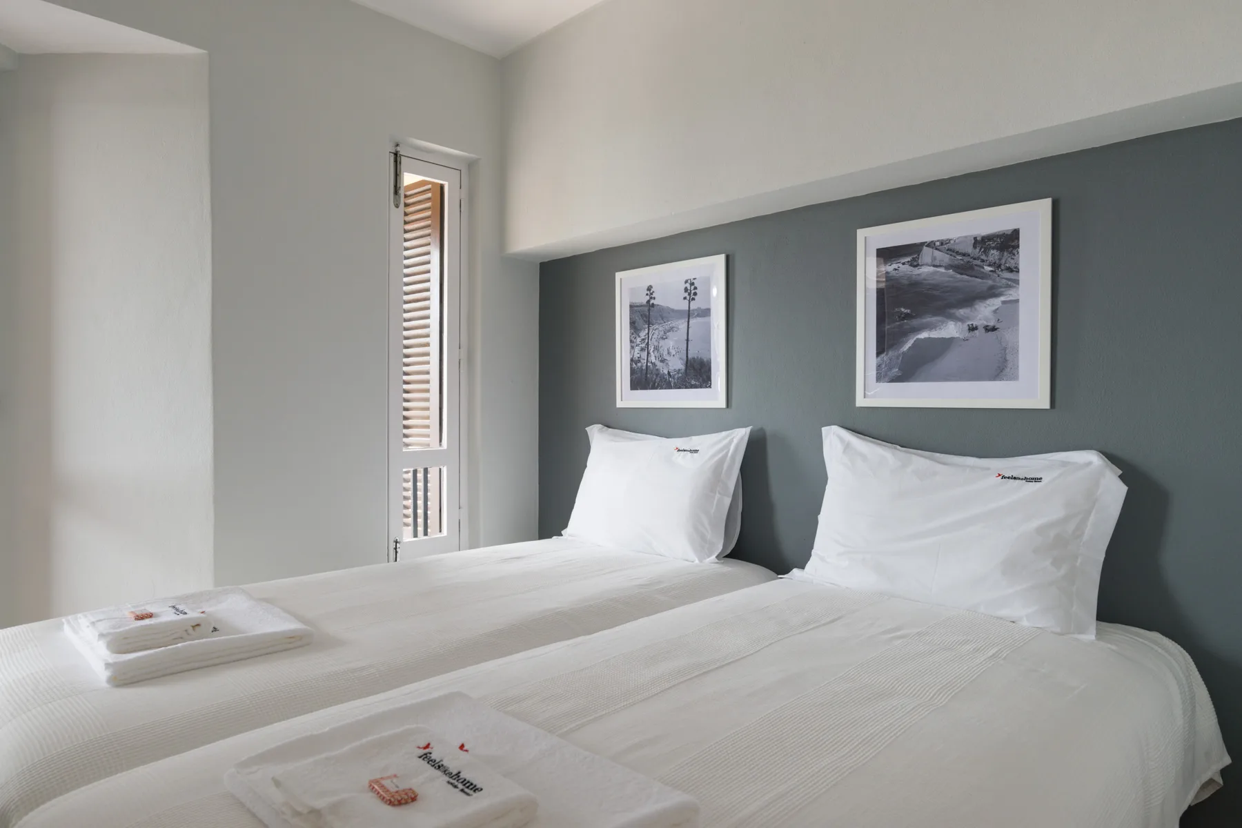 A bedroom with two beds and framed pictures on the wall.