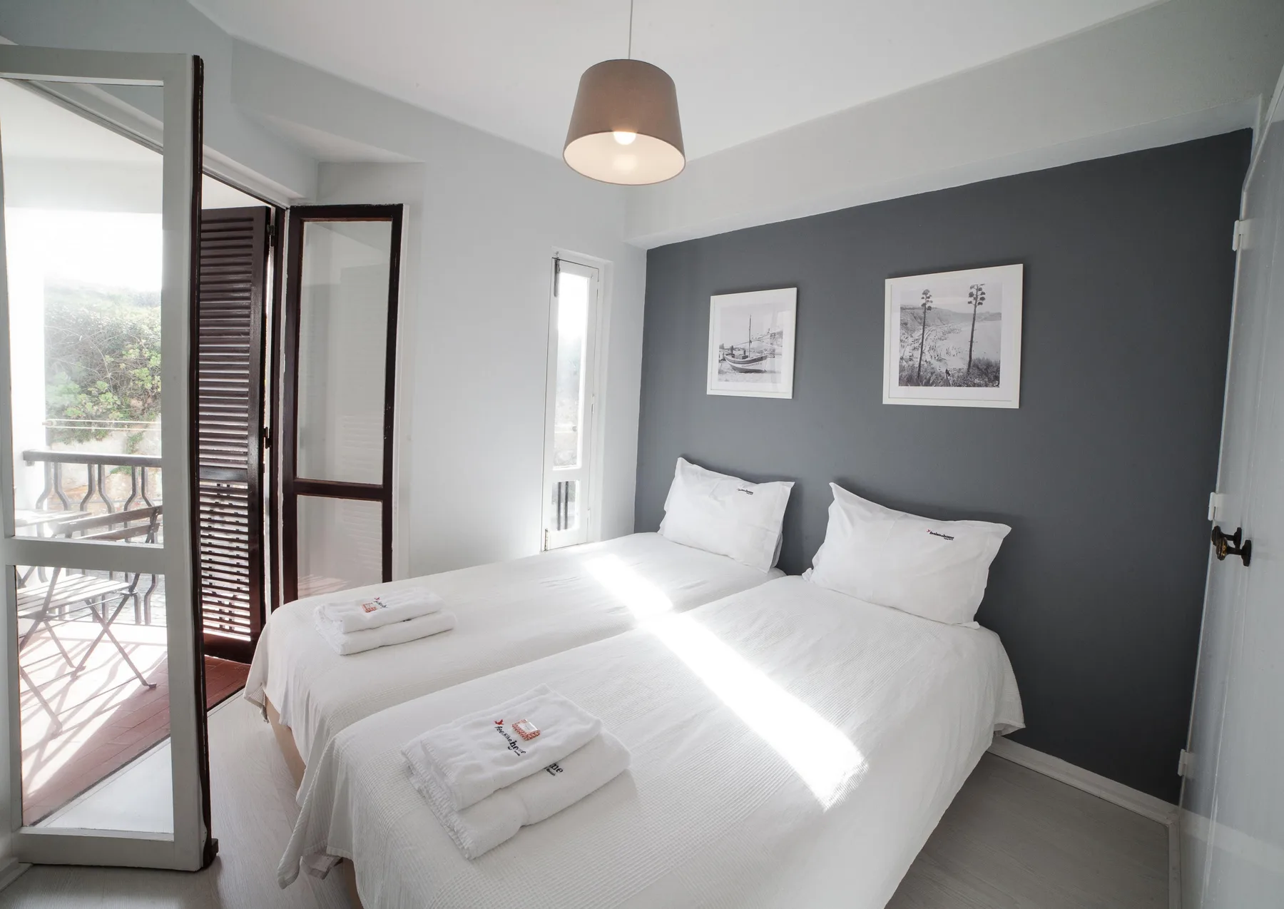 A bedroom with two single beds, white bedding, and framed pictures on a dark wall.