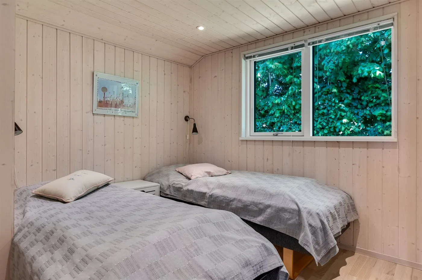 Dormitorio con dos camas y una ventana con vistas a la vegetación.