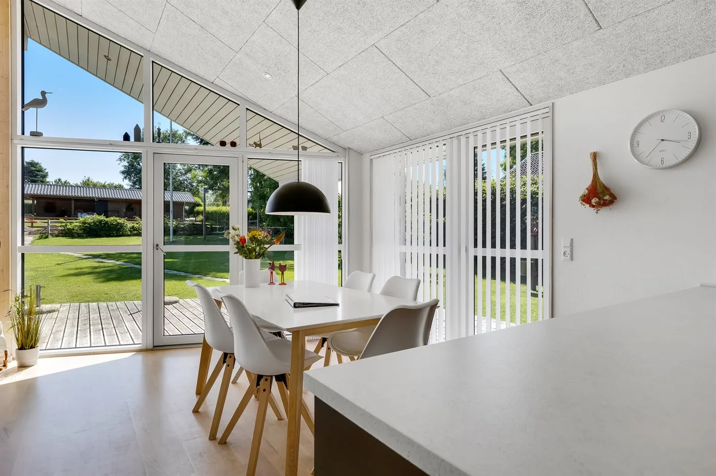 Un comedor luminoso con una mesa junto a grandes ventanas que dan a un césped.