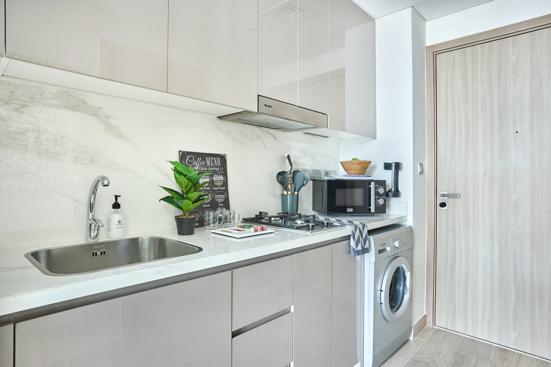 Una cocina moderna con encimera, fregadero, placa de cocina y lavadora.
