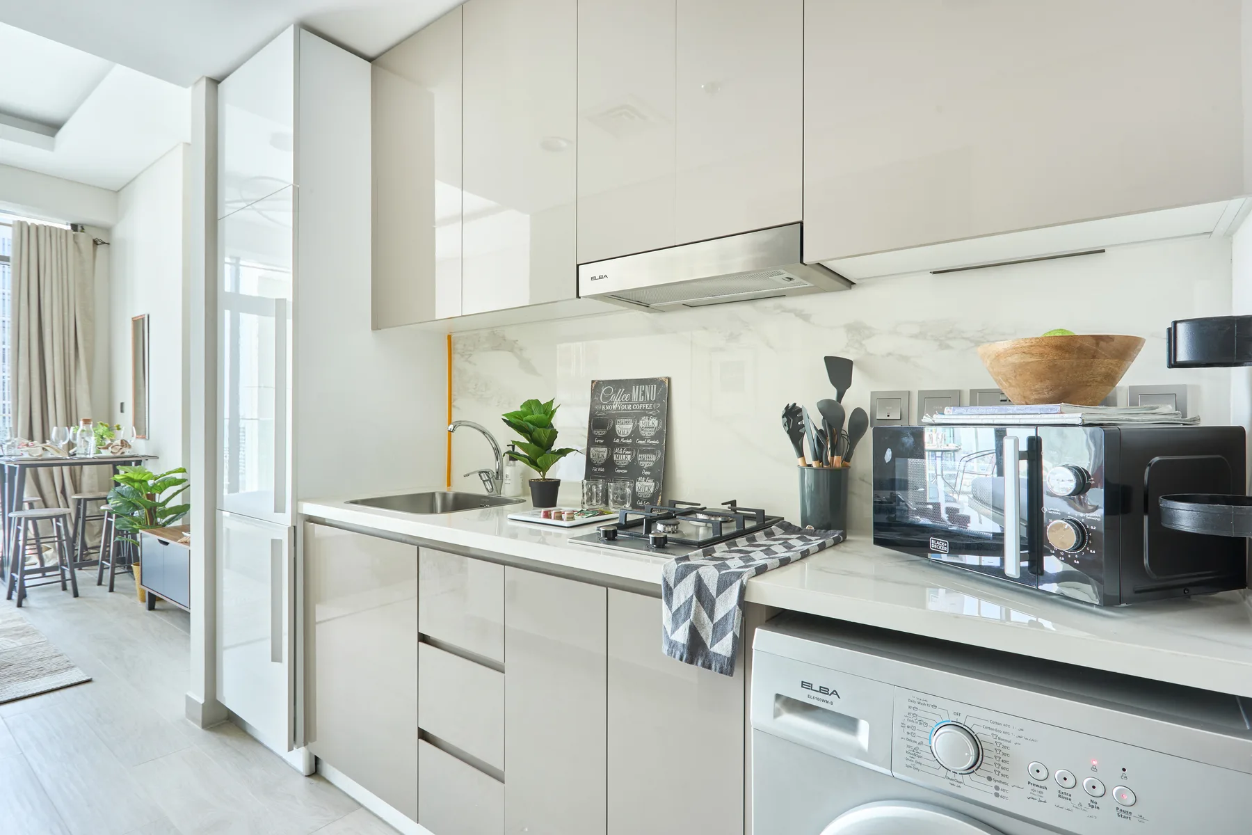 Una cocina moderna y luminosa con encimera, placa de cocina y lavadora.