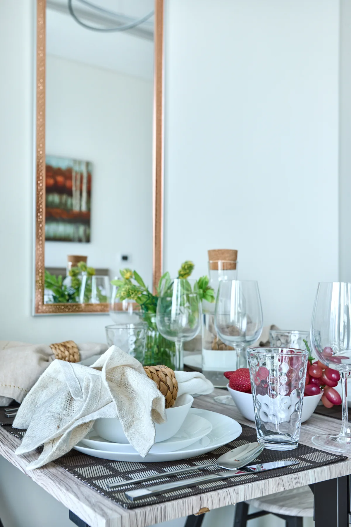 Una mesa de comedor está preparada con platos, vasos y un paño blanco.