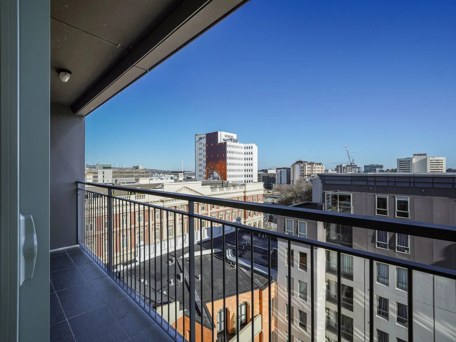 Vista desde un balcón de edificios de la ciudad y cielo despejado en Downtown Haven - Christchurch Holiday Apartment, en Christchurch