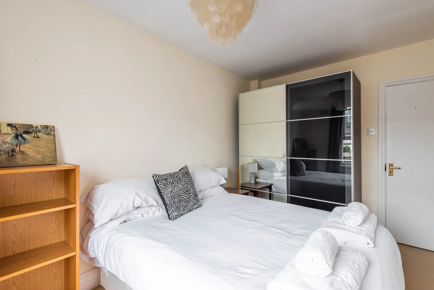 A bedroom with a bed and a mirrored wardrobe.