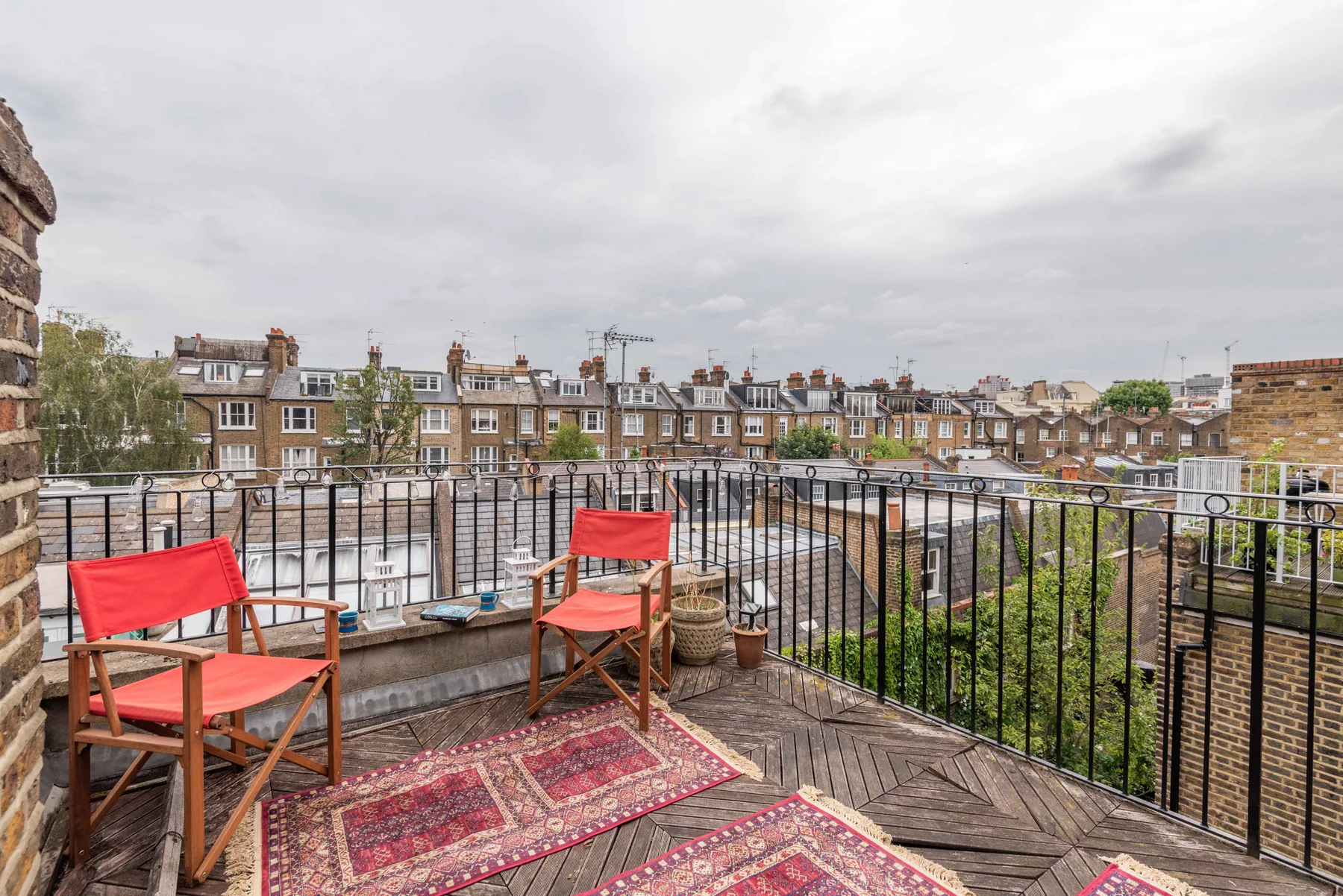 A rooftop terrace with outdoor seating and views of nearby buildings.