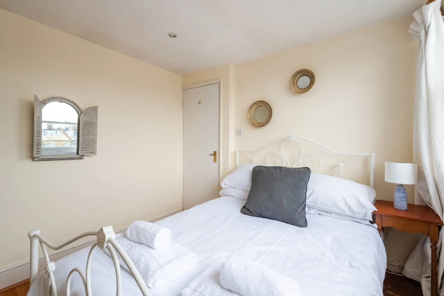 A bedroom with white bedding and a small wooden bedside table.