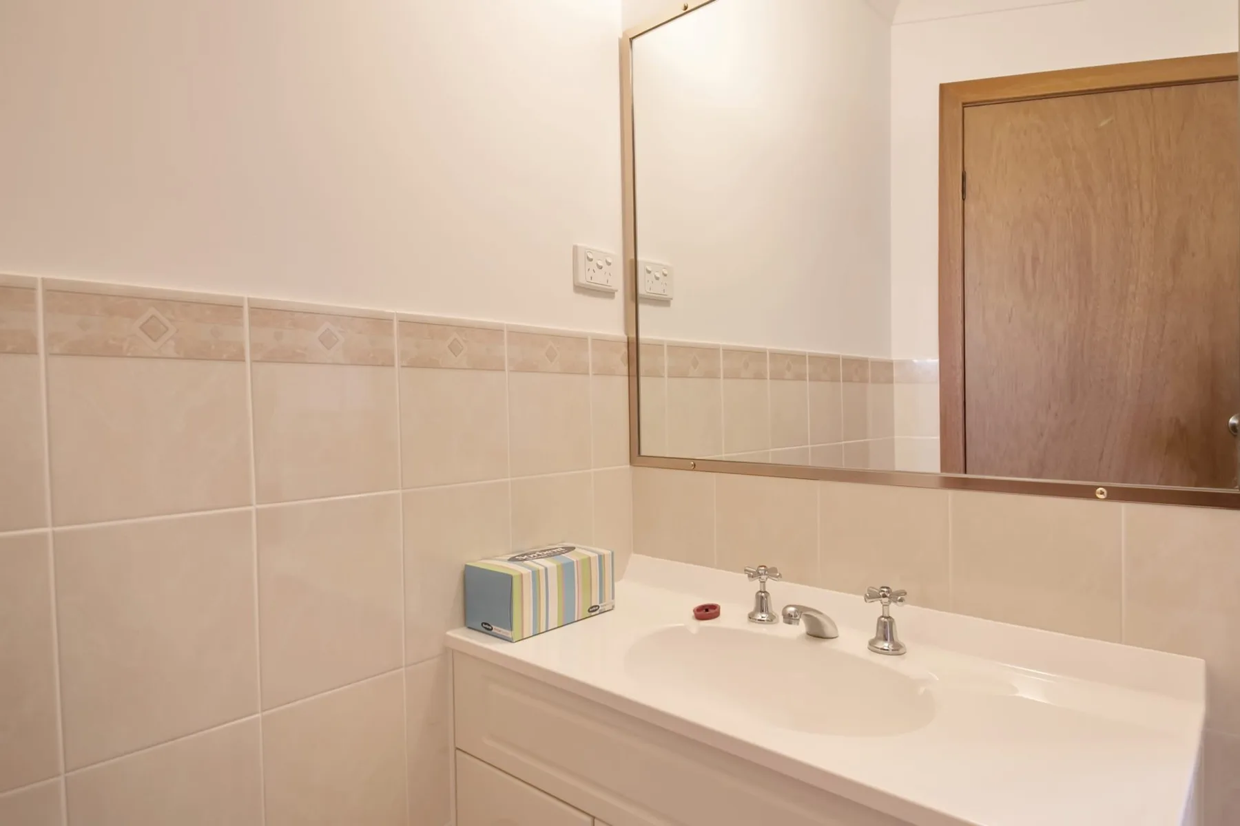 Baño con lavabo, espejo y paredes alicatadas.