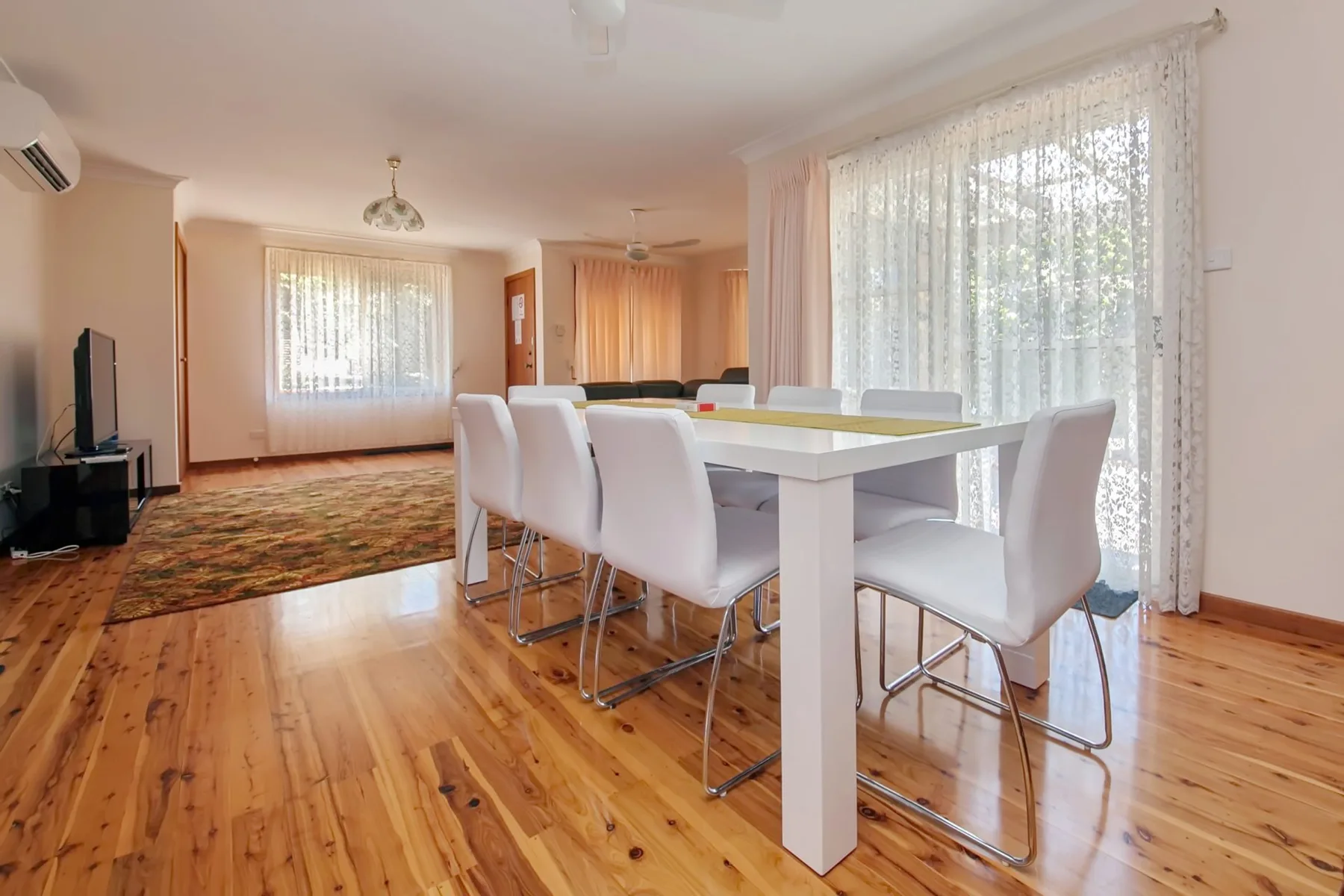 Comedor con una mesa blanca y sillas junto a grandes ventanas.