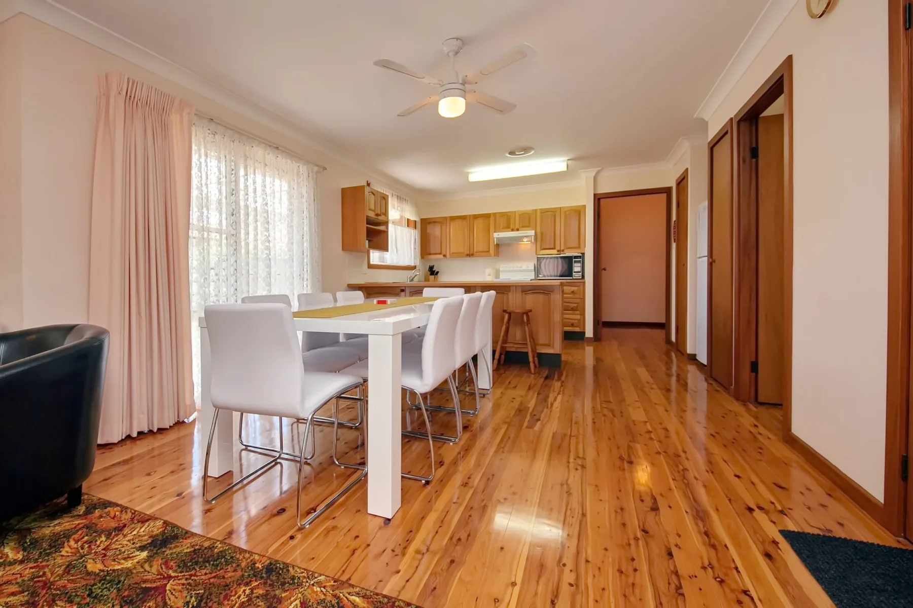 Comedor y cocina con una mesa, asientos y suelo de madera.