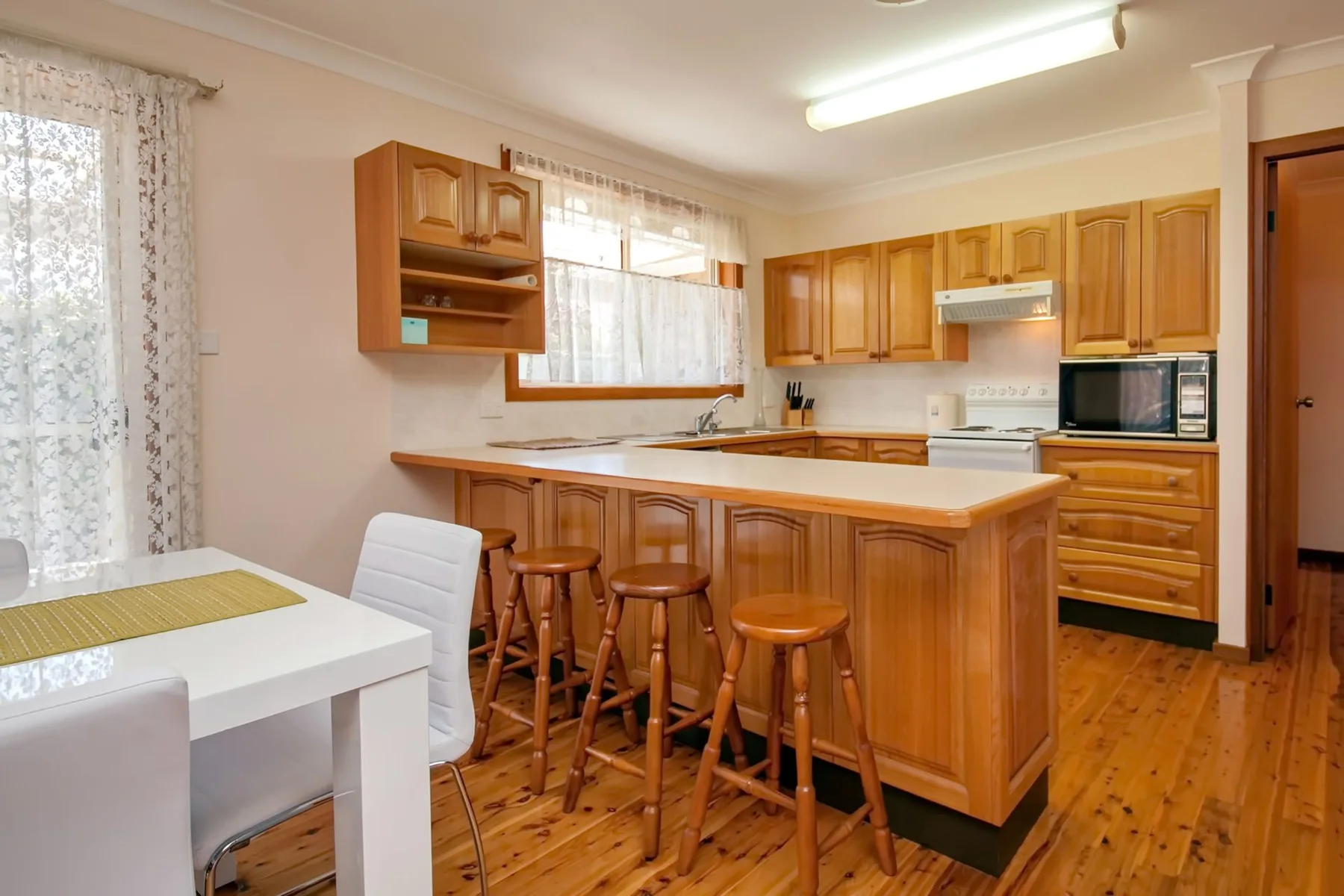 Una cocina luminosa con una isla de madera y una mesa junto a la ventana.