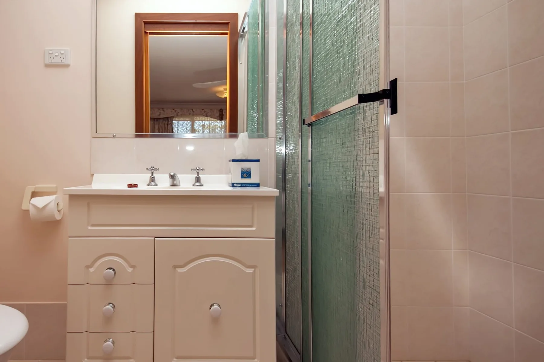 Un lavabo con mueble está junto a una ducha de vidrio.