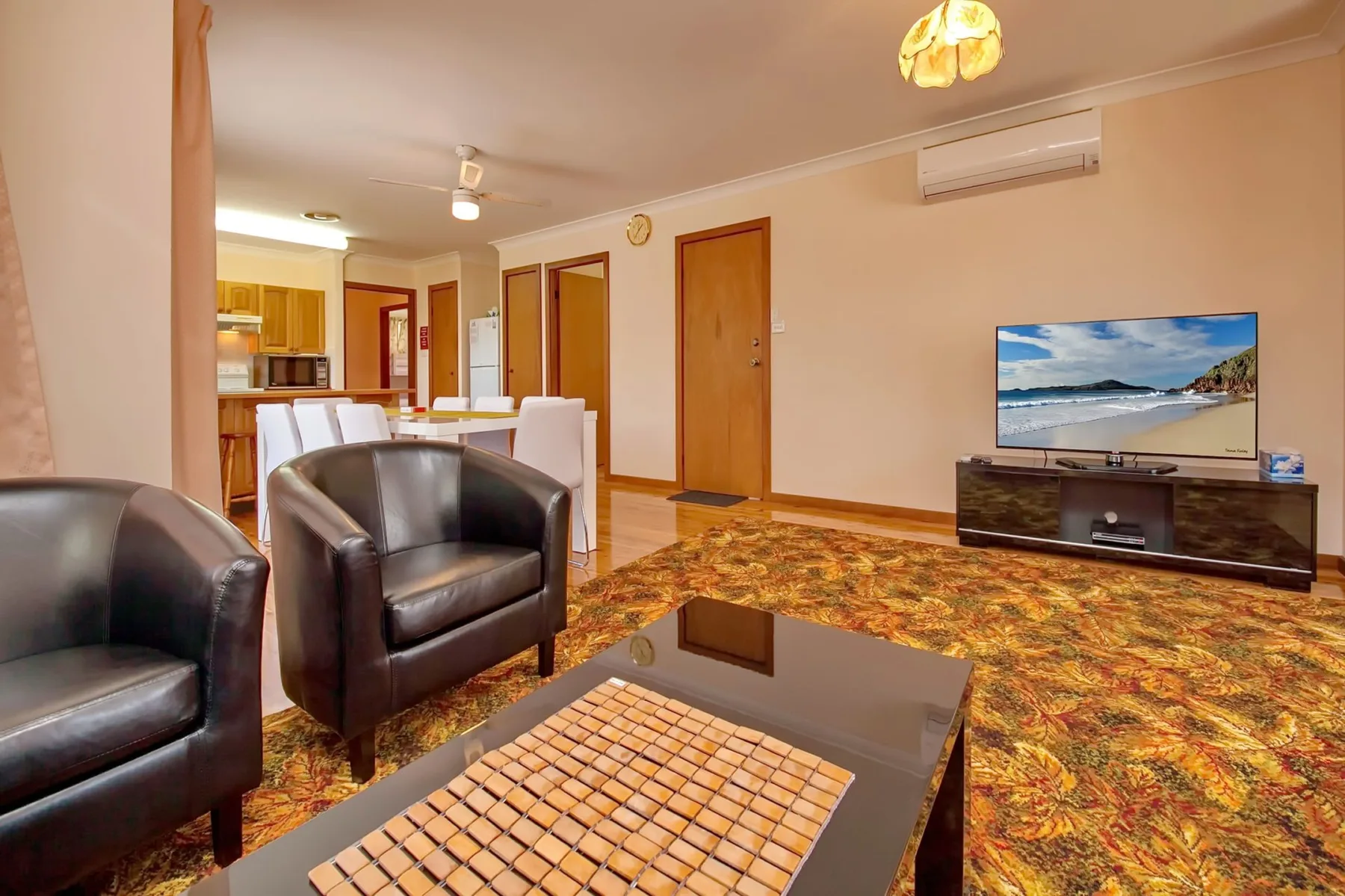 Una sala de estar con asientos oscuros, una mesa de centro y un televisor.