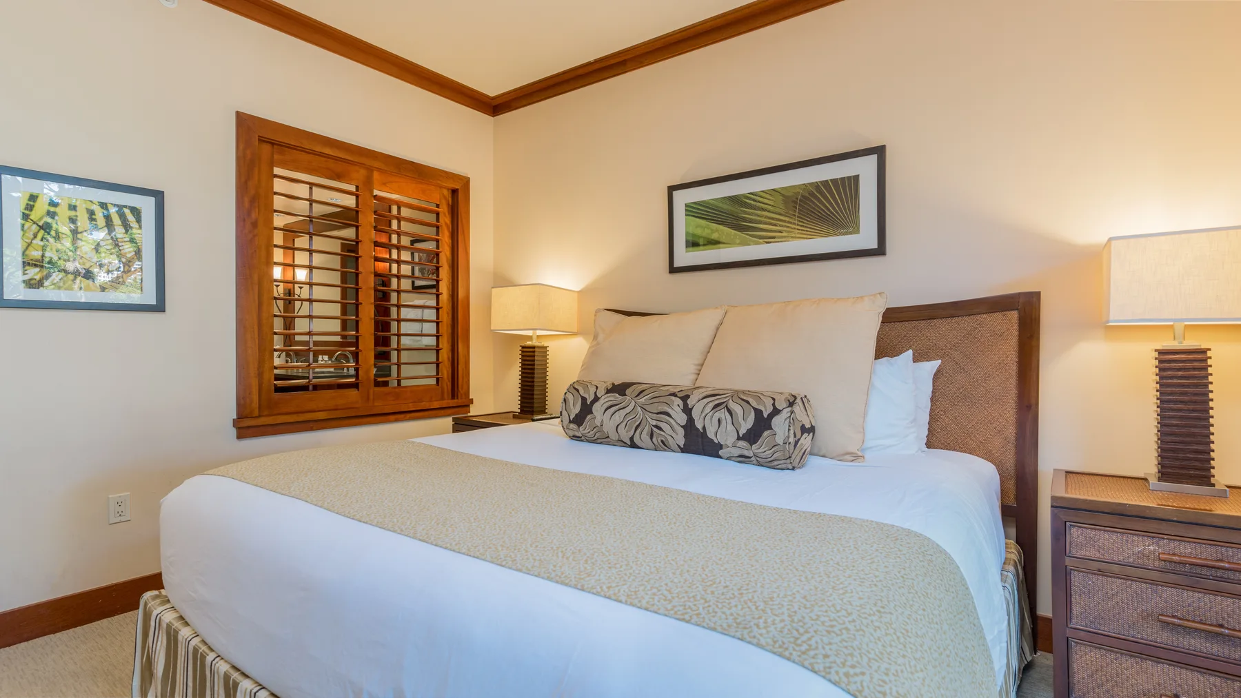 Un dormitorio con una cama bien tendida y contraventanas de madera.