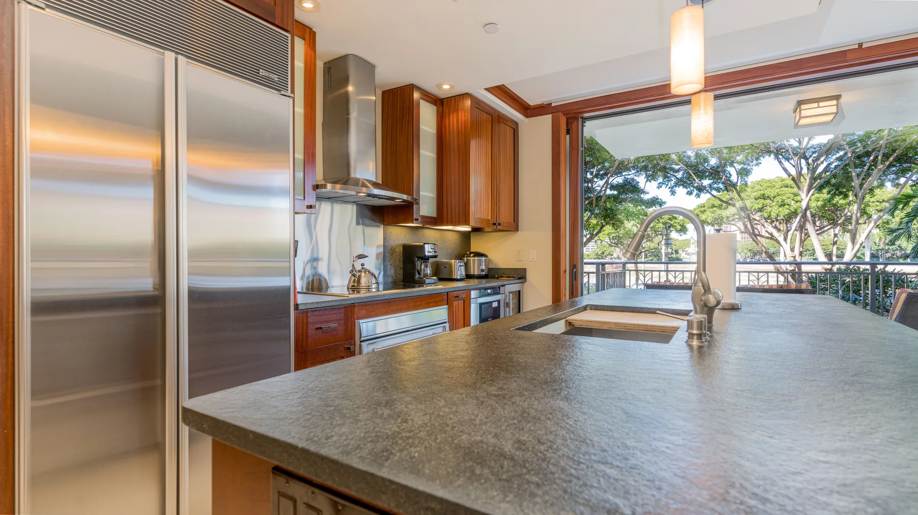 Una cocina moderna con una gran isla se abre a una vista exterior arbolada.