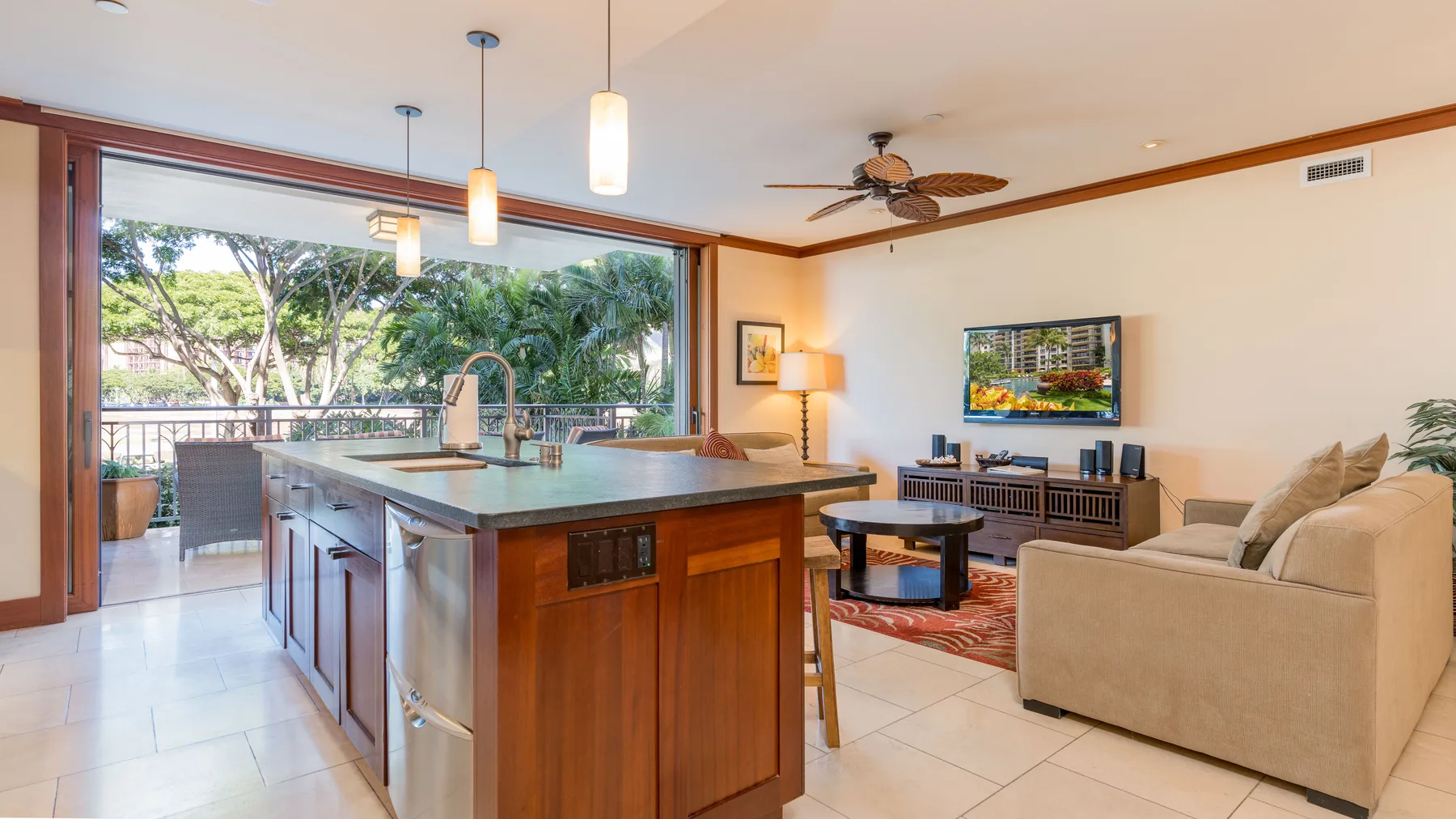 Sala de estar y cocina de concepto abierto, con una isla grande junto a puertas corredizas de vidrio.