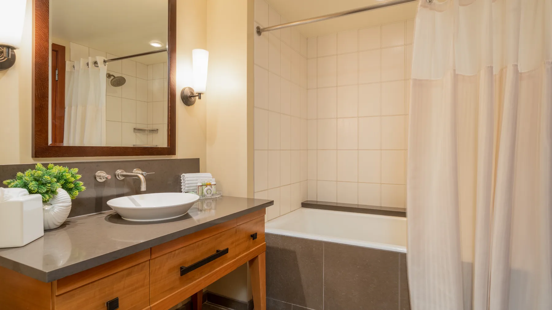 Un baño con lavabo y mueble junto a una bañera con cortina de ducha.