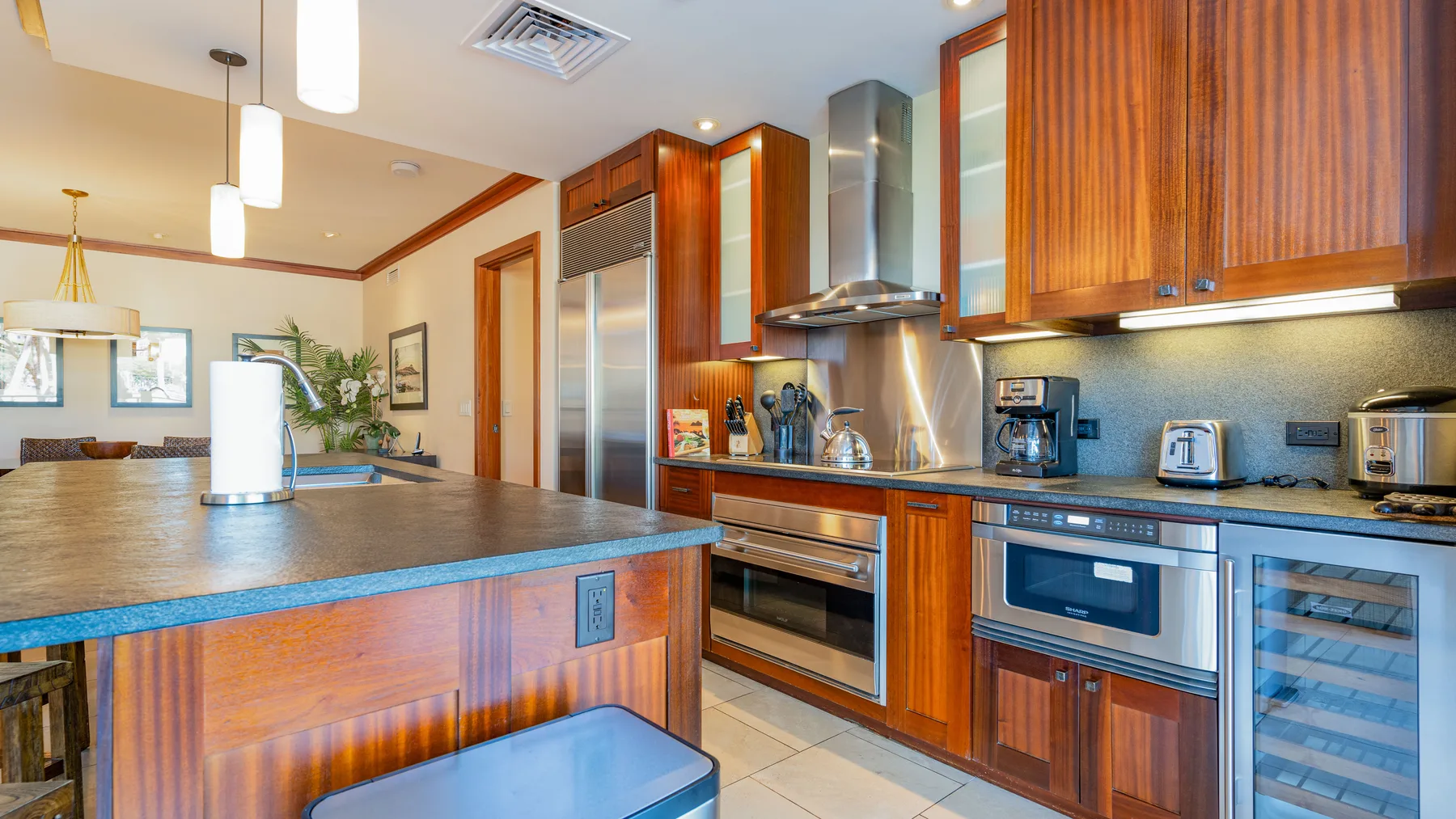 Una cocina moderna con gabinetes de madera, una isla central y electrodomésticos de acero inoxidable.
