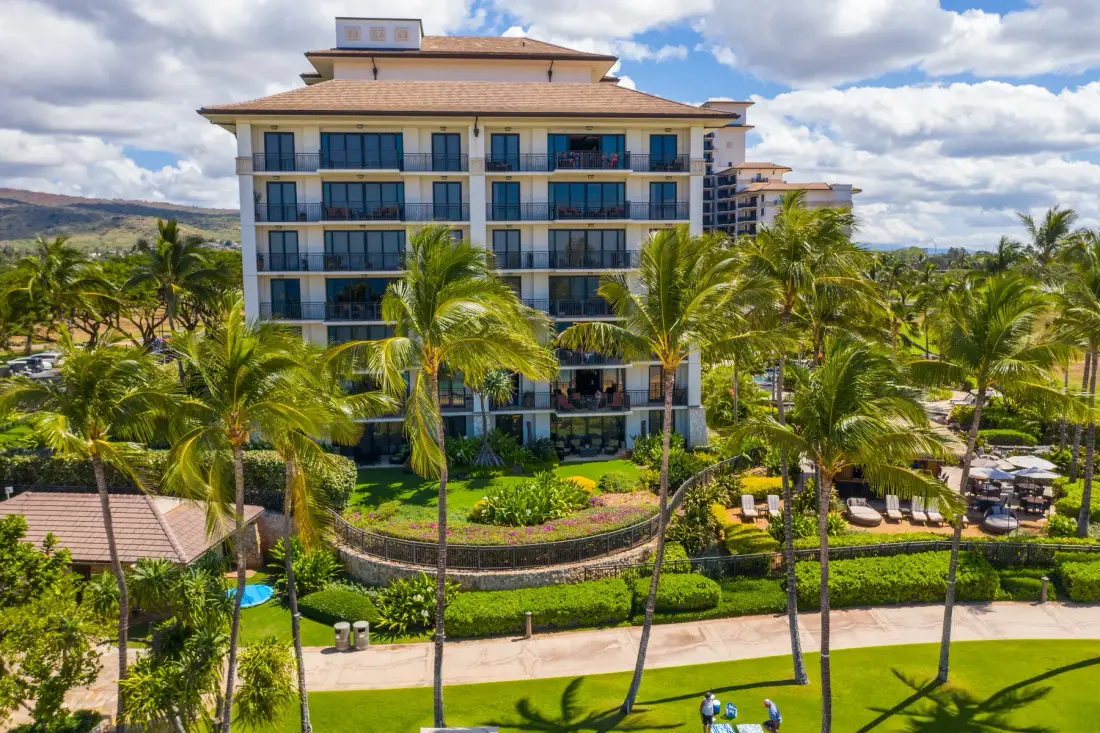Un edificio de varias plantas se alza entre palmeras y jardines.