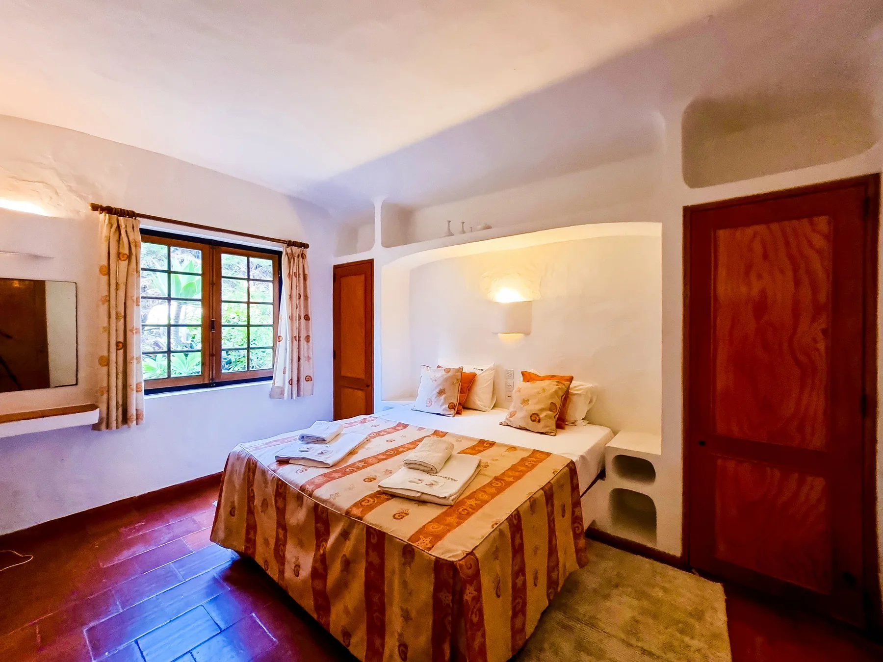 Un dormitorio con una cama doble, ropa de cama estampada y una ventana.
