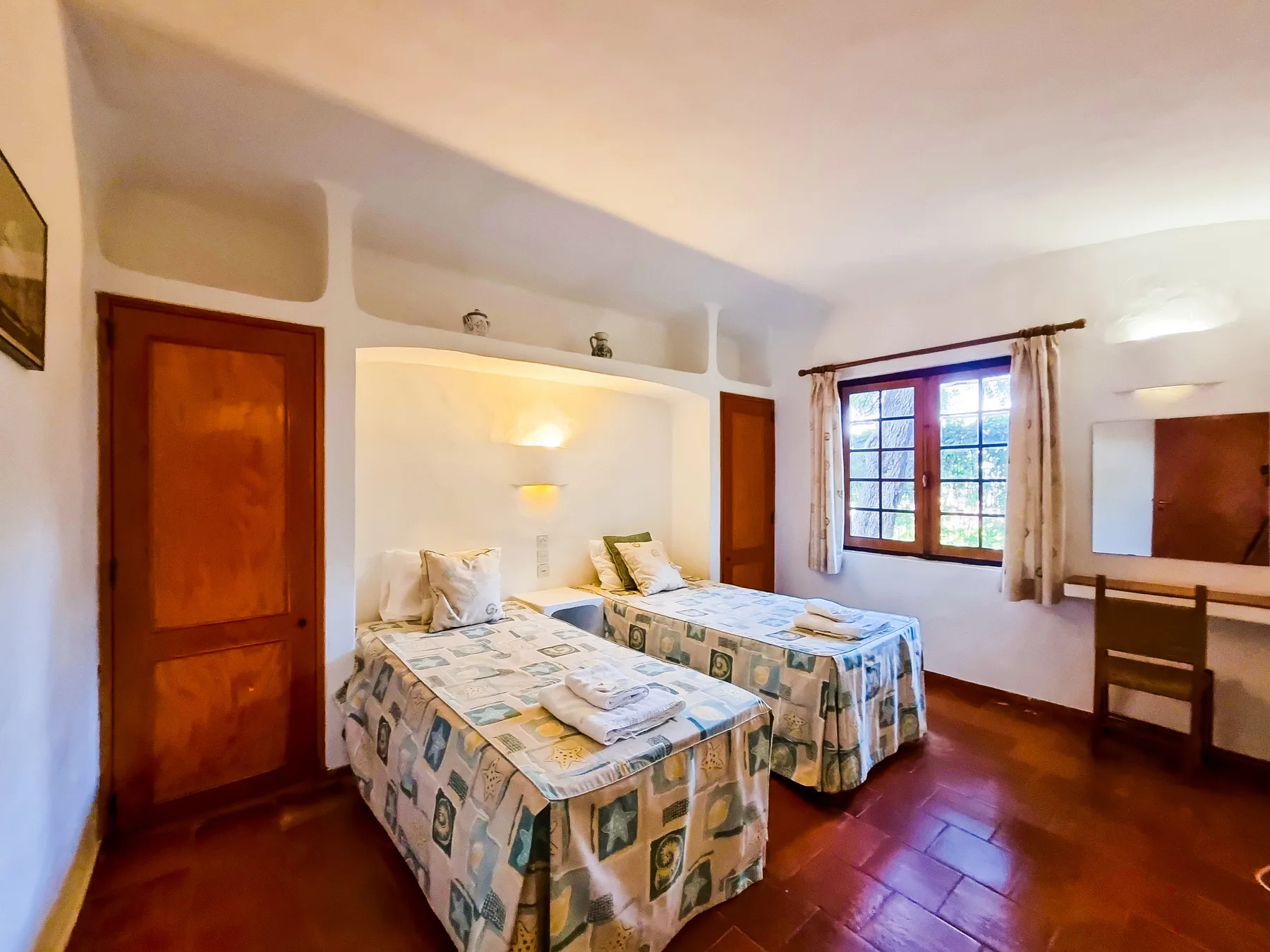 Un dormitorio con dos camas, ropa de cama estampada y una ventana.